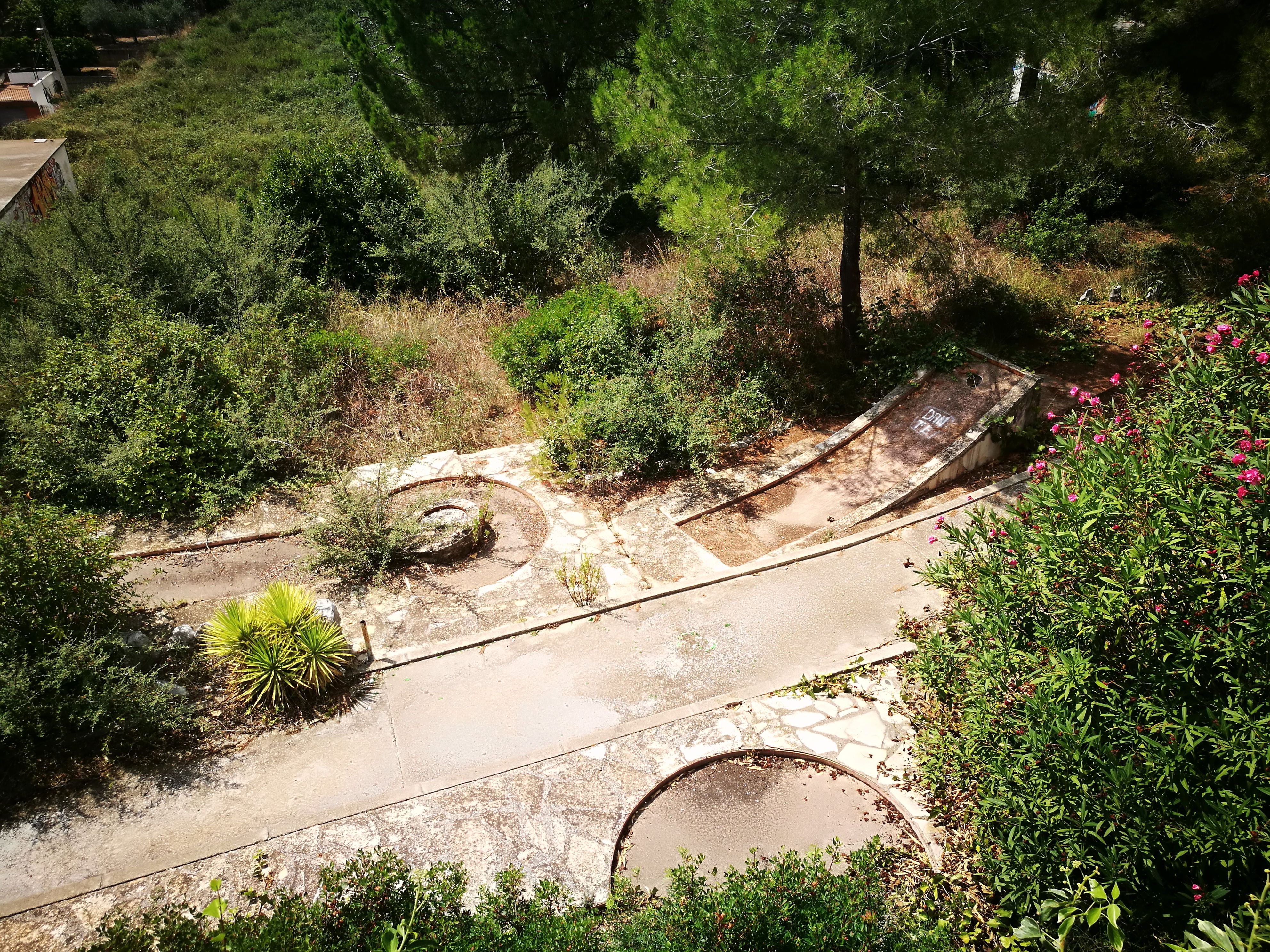 Les restes del minigolf engolit per l'herba i la malesa