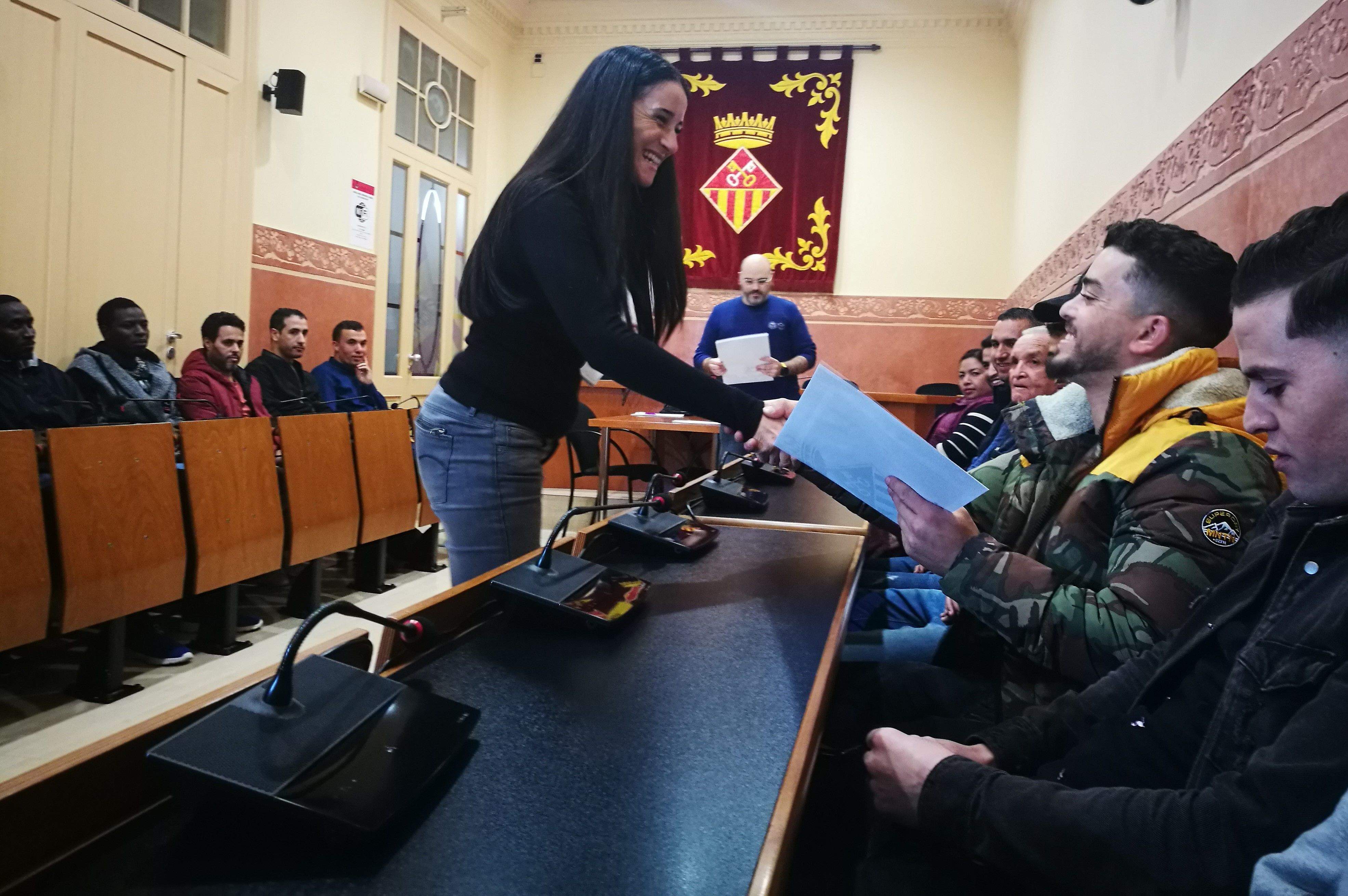 La regidora de Ciutadania, Mª Carmen Cebrián, lliura el certificat d'acollida a un dels assistents a la sala de plens de Rubí. FOTO: Redacció
