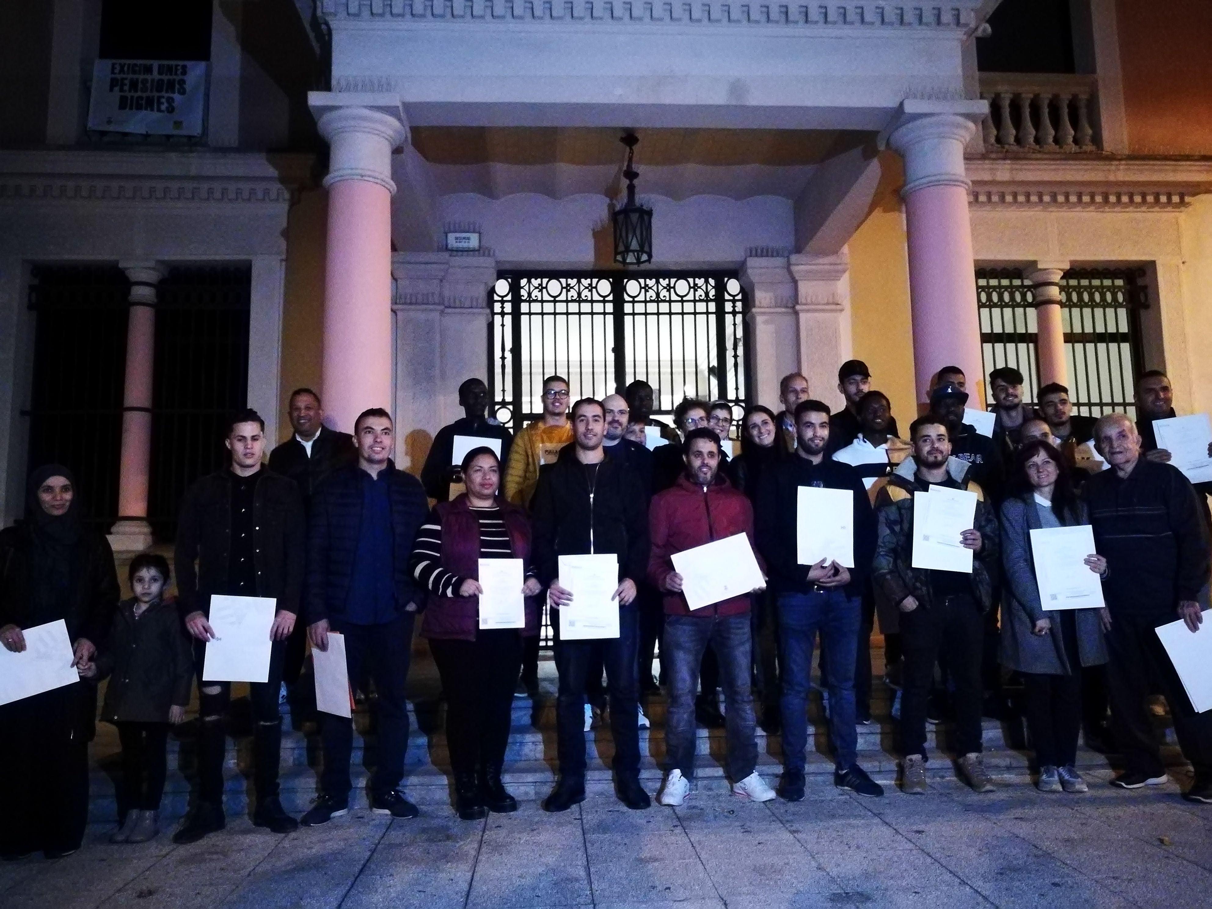Les 22 persones nouvingudes amb els seus certificats de reconeixement a les portes de l'Ajuntament. FOTO: Redacció