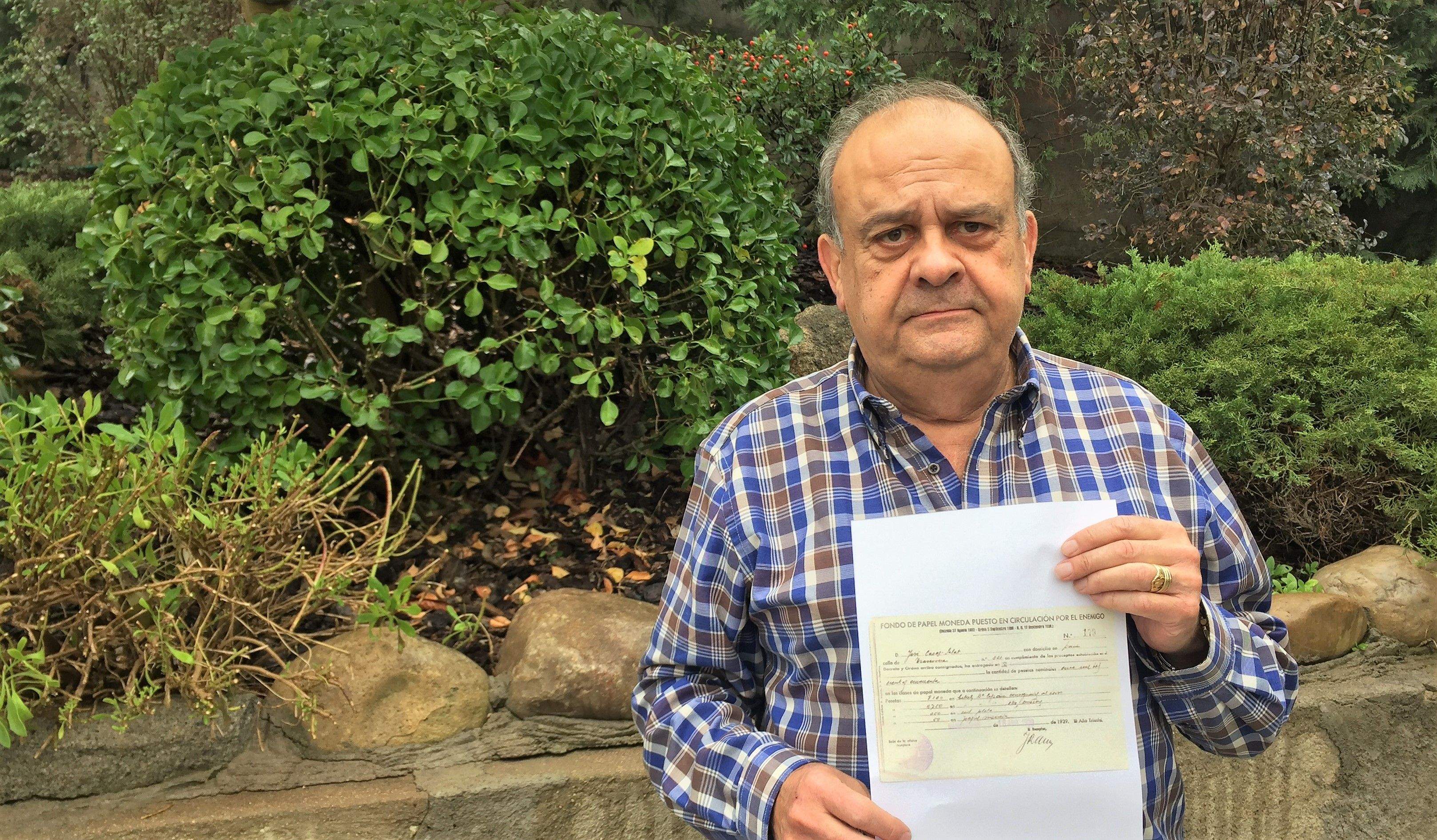 Joaquim Gracia sosté la còpia d’un rebut original on consten diners confiscats a la seva família pel govern franquista. 
