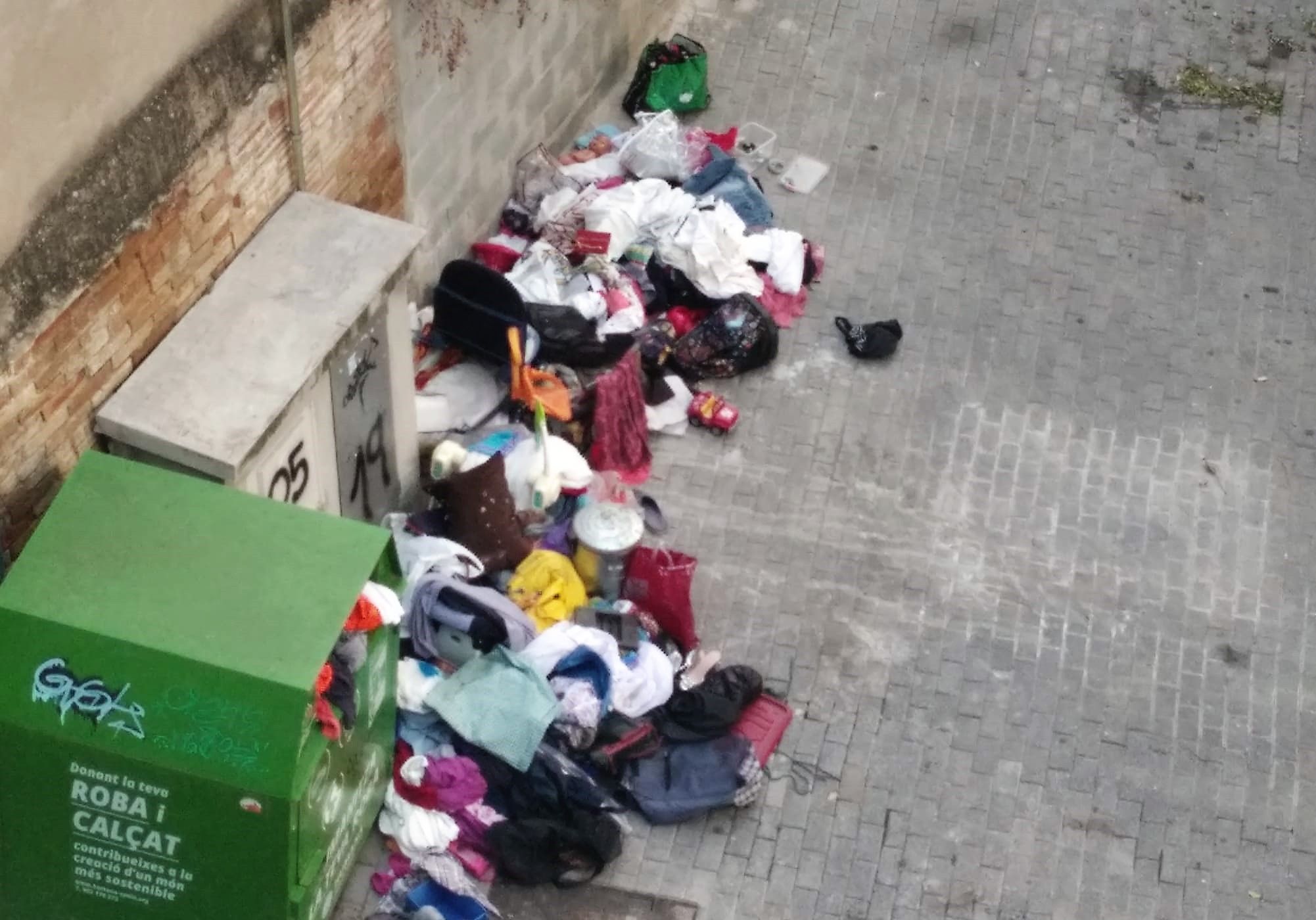 Restes de roba al voltant del contenidor Humana al carrer Montserrat. FOTO: Cedida