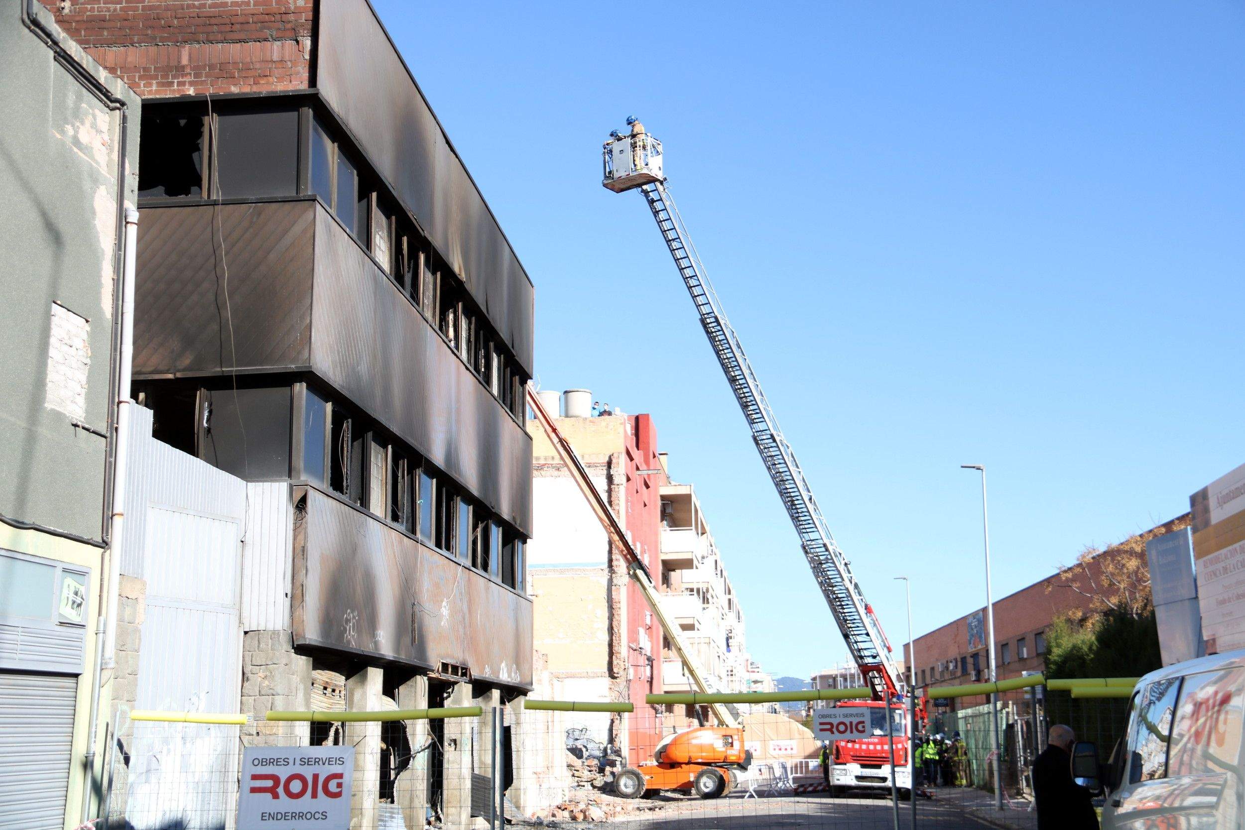 Una grua amb bombers supervisant les tasques d'enderroc després de l'incendi de la nau de Badalona. FOTO: ACN