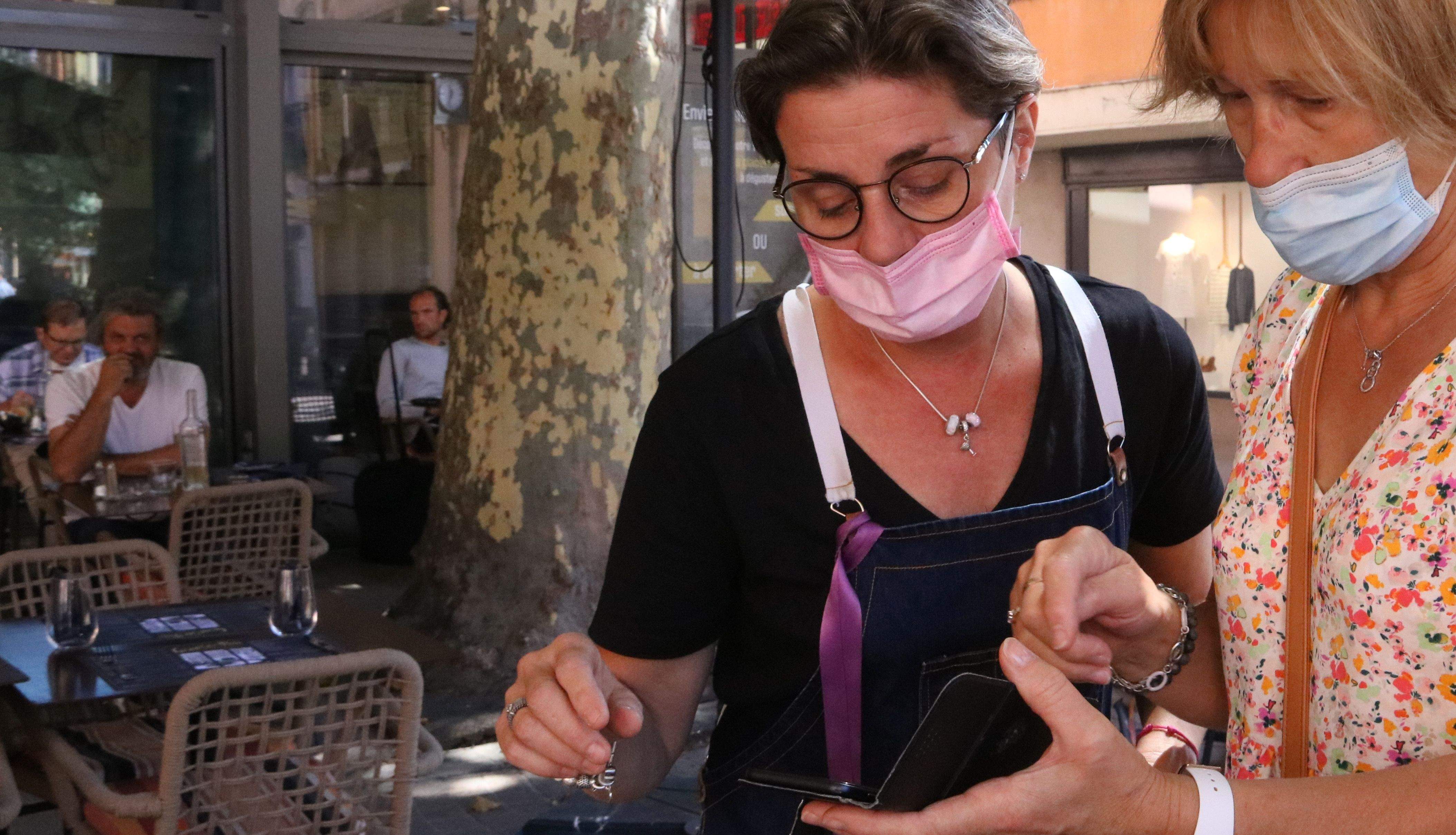 Una clienta mostra el passaport covid-19 en un restaurant. FOTO: Gemma Tubert (ACN)