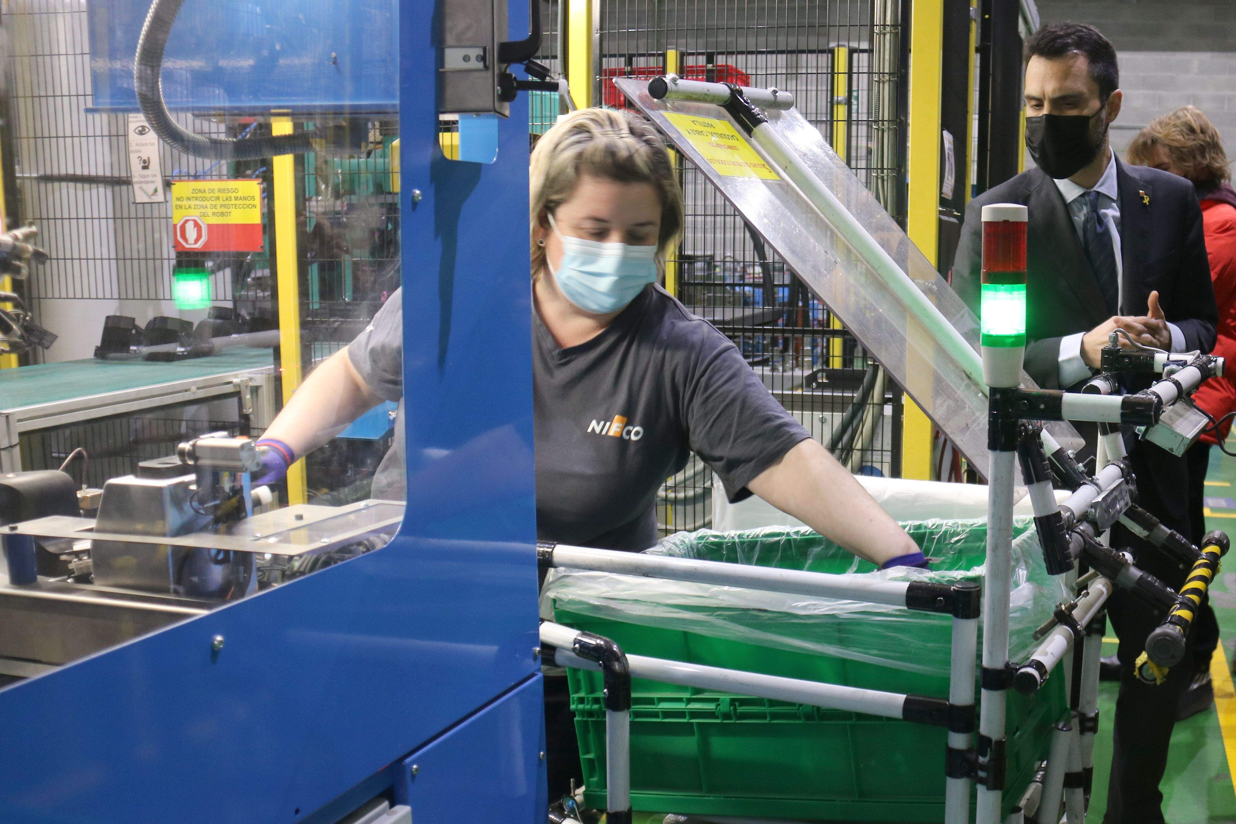 Una operària a la planta de Tag Automotive de Terrassa amb el conseller d'Empresa i Treball, Roger Torrent. FOTO: Albert Segura Lorrio (ACN)