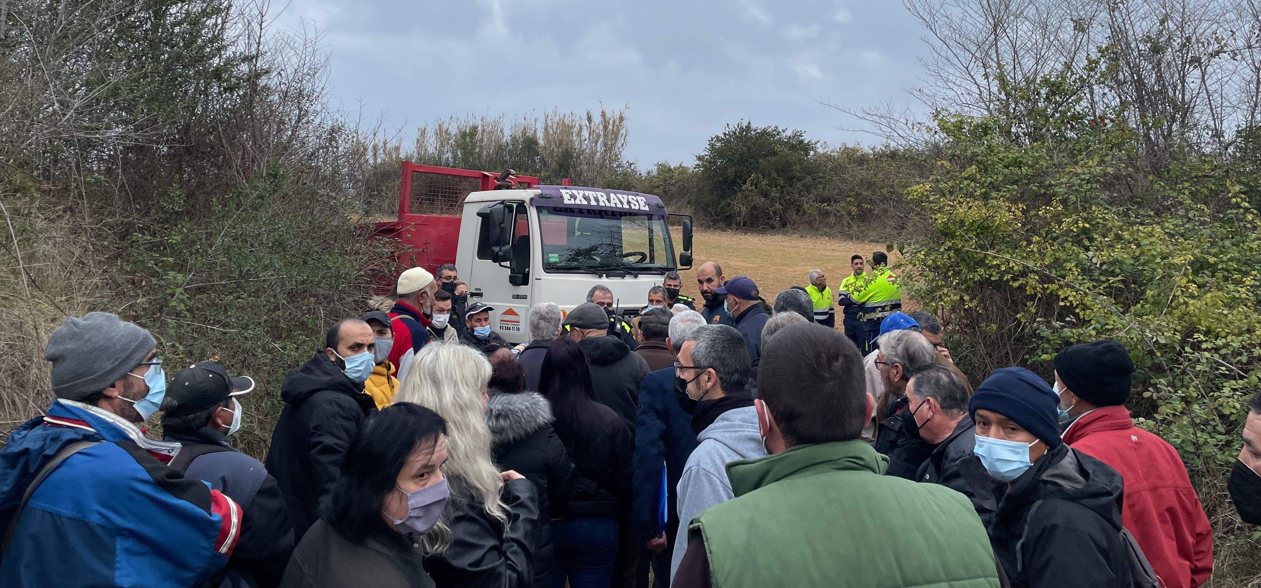Moment en el qual la Policia local els hi comunica a les persones congregades que hi ha una autorització judicial per desmantellar la zona, juntament amb un camió i els operaris al fons. FOTO: NHS Moment en el qual la Policia local els hi comunica a les persones congregades que hi ha una autorització judicial per desmantellar la zona, juntament amb un camió i els operaris al fons. FOTO: NHS
